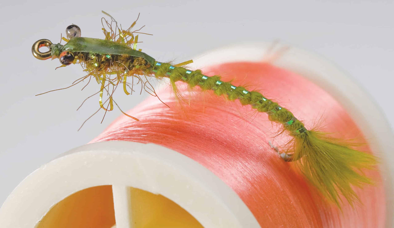 Dubbed fly next to a spool of tying thread